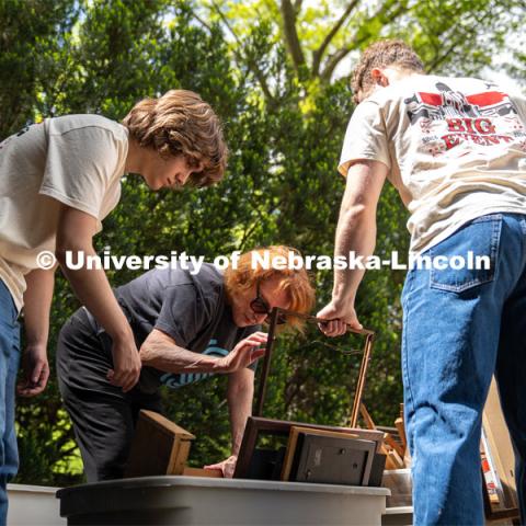 Phi Kappa Theta members Ryan Richert (left) and Alex Buescher (right) sort through a tub of picture frames with homeowner Margaret Berry during the Big Event. May 4, 2024. Photo by Kirk Rangel for University Communication.